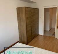 A wardrobe with a wooden decor in a 2-room apartment. White wall and floor with wooden decor.