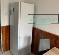 Kitchen in a 2-room apartment, refrigerator, wooden paneling, gray chair, dining table.