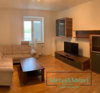 Living room with a beige sofa, wooden furniture, and a floor with a wood pattern.