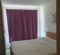 A bedroom with purple curtains, a children's theme, and a wooden decor floor in a two-room apartment.