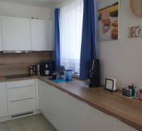 A kitchen in a 2-room apartment with white cabinets and a wood-patterned floor.