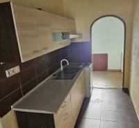 A kitchen in a 2-room apartment with brown tiles and a wooden decor floor.