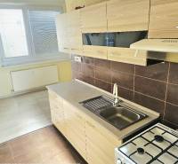 A kitchen in a 2-room apartment with white cabinets and a wood-patterned floor.