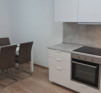 A kitchen corner in a 2-room apartment with a wooden decor floor and a dining table.