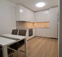 A kitchen in a 2-room apartment with white cabinets and a wood-patterned floor.