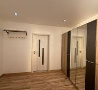 A room in a 3-room apartment with a floor featuring a wooden decor and a mirrored wardrobe.