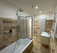 A bathroom in a 3-room apartment with a bathtub and a shower, tiled with light tiles.