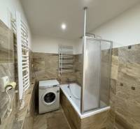A bathroom in a 3-room apartment with a shower, bathtub, and washing machine.