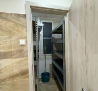 A small storage room in a 3-room apartment with shelves and a bucket.