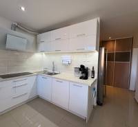 A kitchen unit in a 3-room apartment with a wooden decor floor and appliances.
