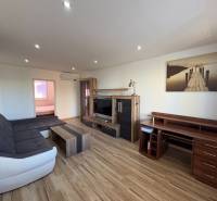 Living room in a three-room apartment with a wooden decor floor and a comfortable sofa set.