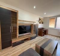 Living room in a three-room apartment with a wooden decor floor and modern furniture.