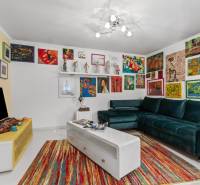 A colorfully decorated living room of a family house with a green sofa and artworks on the walls.
