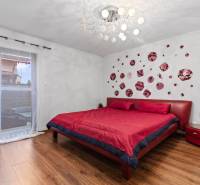 Bedroom with a red bed, wall decoration, and wooden decor flooring in a family house.