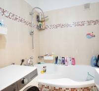 A bathroom in a 3-room apartment with a bathtub, tiles, and a washing machine.