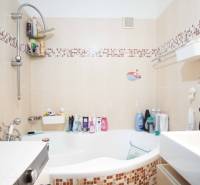 Bathroom with a bathtub in a 3-room apartment, tiles with a mosaic pattern, shower faucet.