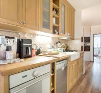 A kitchen of a 3-room apartment with wooden kitchen cabinets and a floor with a wood design.