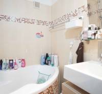 Bathroom in a 3-room apartment with a bathtub, sink, and shelves with cosmetics.
