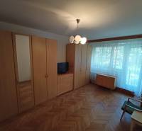 A room in a 2-room apartment with wardrobes, a television, and a floor with a wooden decor.