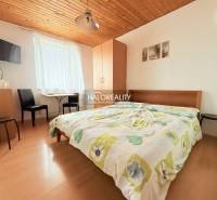 A hotel room with a double bed, a television, a table, and a floor with a wooden decor.