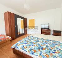 A room with a bed, wardrobe, television, and a wooden-patterned floor, typical for hotels and guesthouses.