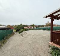 Exterior in Podhájska next to hotels and guesthouses, a courtyard covered with gravel and a shelter.