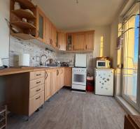A kitchen in a 2-room apartment with wooden decor and appliances, including a small stove.