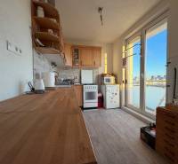 A kitchen in a 2-room apartment with wooden decor and appliances, view from the balcony.