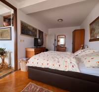 A room in a 5 or more bedroom apartment with a bed, art on the walls, and a floor with a wood decor.