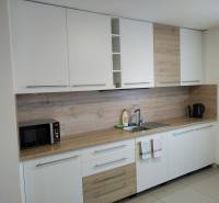 A kitchen in a cottage with white cabinets and a wood-patterned floor.