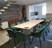 Dining room in a cottage with a large table, modern chairs, and a kitchenette.