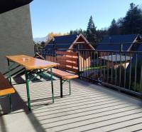 The balcony of the cottage in Stráne in Martin with a wooden bench and table, surrounded by nature.