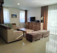 Living room in a cottage with a sofa, television, and wooden decor flooring.