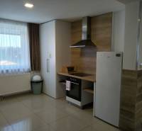 Interior of a cottage with a kitchenette and white appliances, tiled floor.