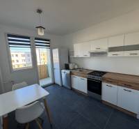 A kitchen in a 3-room apartment with white furniture and a dining table.