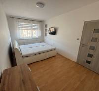 A bedroom with a double bed, wooden decor flooring, and furniture in a 3-room apartment.