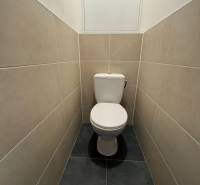 A toilet in a 3-room apartment with light-colored tiles and a simple design.
