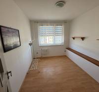 A bright room in a 3-room apartment with a wooden decor floor and wall shelves.