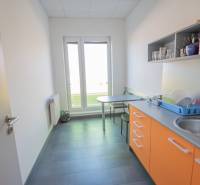A kitchenette in the office with orange cabinets, a sink, and a seating table.
