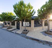 A family house in Most pri Bratislave with a stone fence and tree planting.