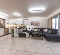 A bright living room in a family house with a kitchen and a large sofa.
