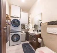 Bathroom in a family house with a washing machine, dryer, sink, and storage space.