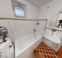 A bathroom in a family house with a bathtub, sink, boiler, and tiled floor.