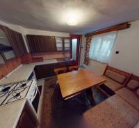 A kitchen in a family house with wooden cabinets, a stove, and a dining table.