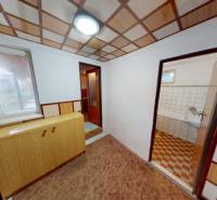 An interior in a family house with a wooden decor floor, a cabinet, and an entrance to the bathroom.