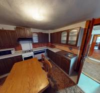 A kitchen in a family house with wooden furniture, a table, and appliances.