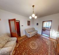 A living room of a family house with a colorful carpet, sofas, and a wooden wall unit.