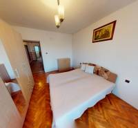 Bedroom with a bed, wardrobe, and wooden decor flooring in a family house.
