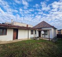 A family house in Bojná with a grassy yard and a gable roof under a blue sky.
