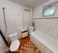A bathroom in a family house with a bathtub, toilet, and heating system, tiled.